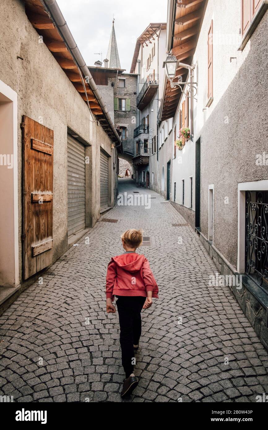 Rear view of boy walking down a narrow lane in Bormio, Lombardy, Italy. Stock Photo