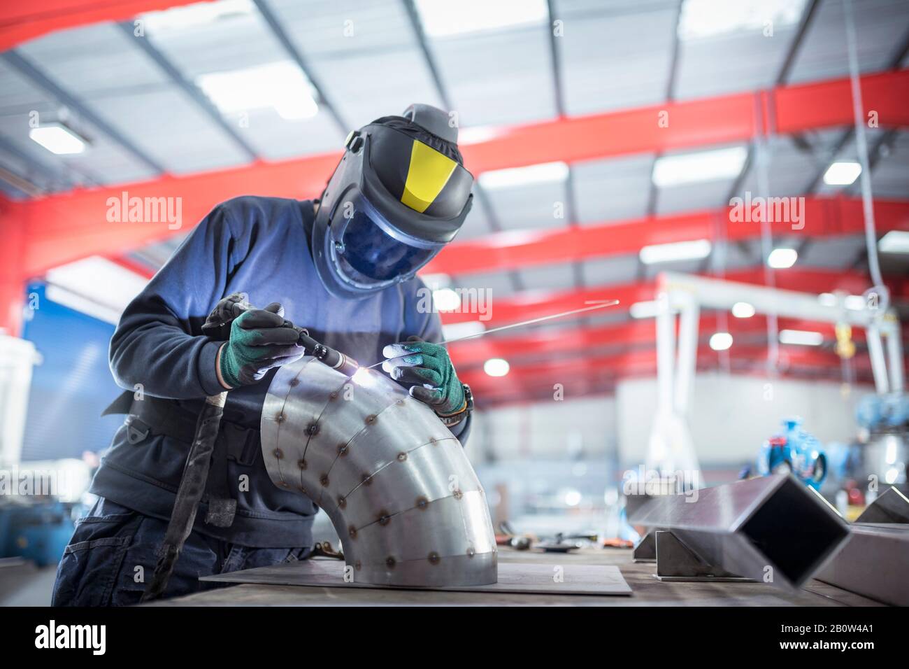 Welder spot welding pipe bend in metal fabrication factory. Stock Photo