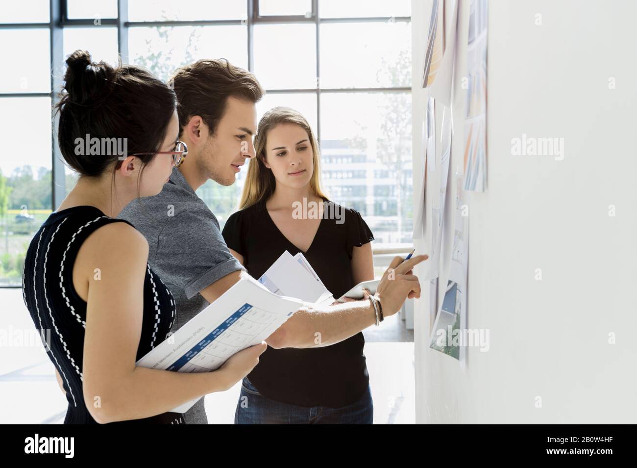 Three young architects standing at whiteboard, discussing design ideas Stock Photo Alamy