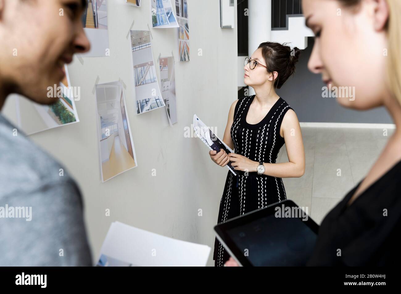 Three young architects standing at whiteboard, discussing design ideas