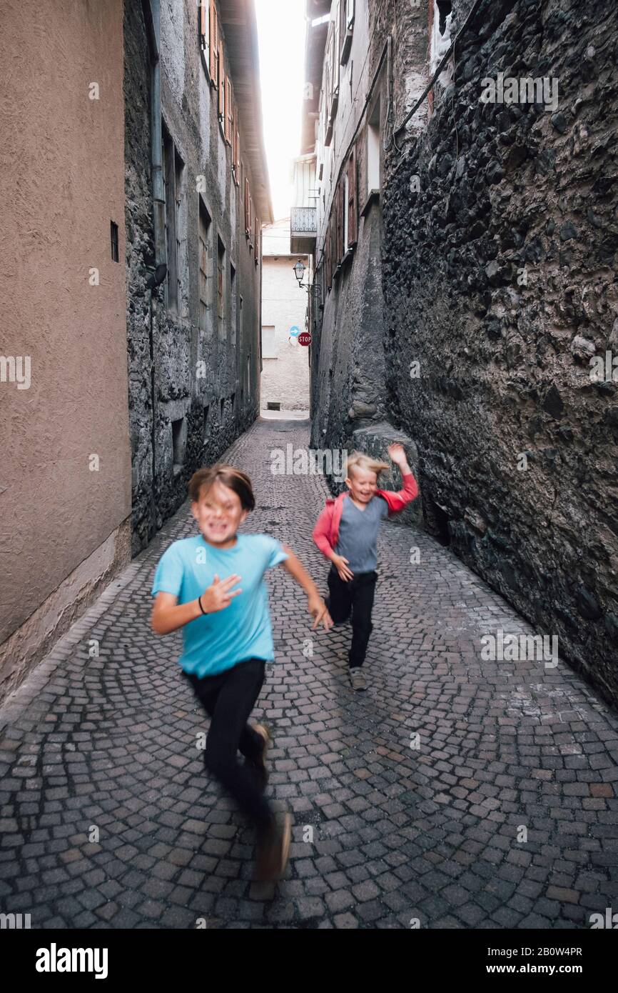 Two boys running down a narrow lane in Bormio, Lombardy, Italy. Stock Photo