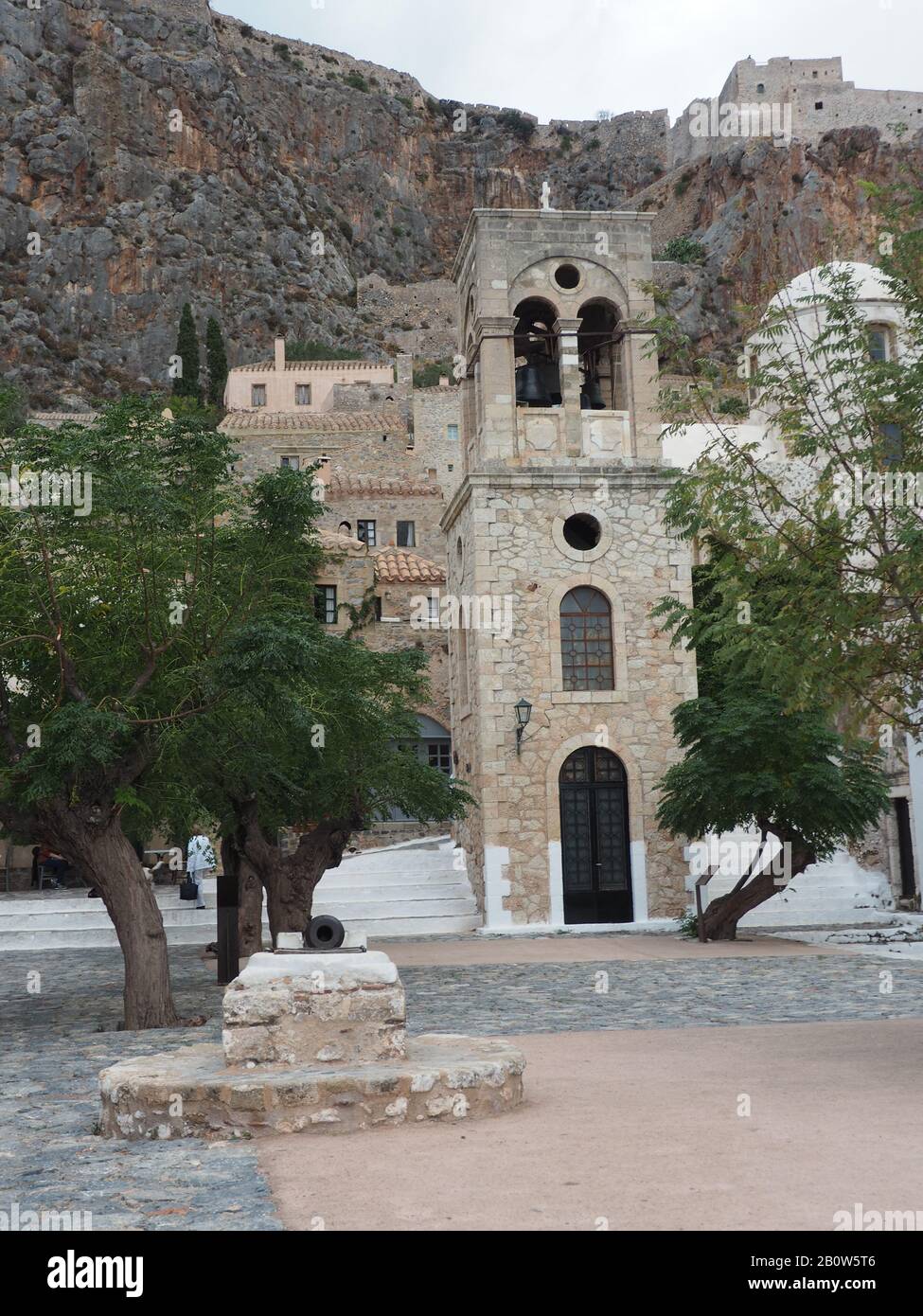 Elkomenos Christos church tower in the central square of walled, island city of Monemvasia, Laconia, Peloponnese, Greece. Ruins on the hill behind. Stock Photo