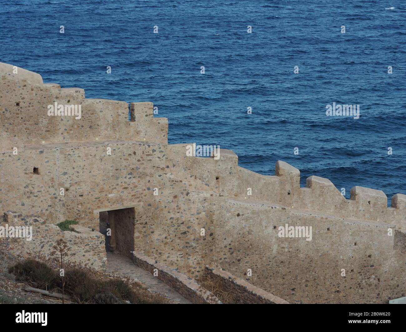 Stone wall of the walled town of Monemvasia, Laconia, Peloponnese, Greece, set against a blue sea. Stock Photo