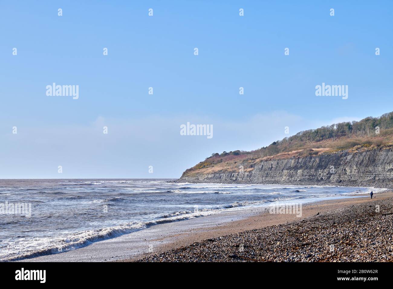 Waves from the English Channel break on the shingle beach of Lyme Bay, Lyme Regis, Dorset, England with the cliffs of the Heritage (Jurassic) Coast, a Stock Photo