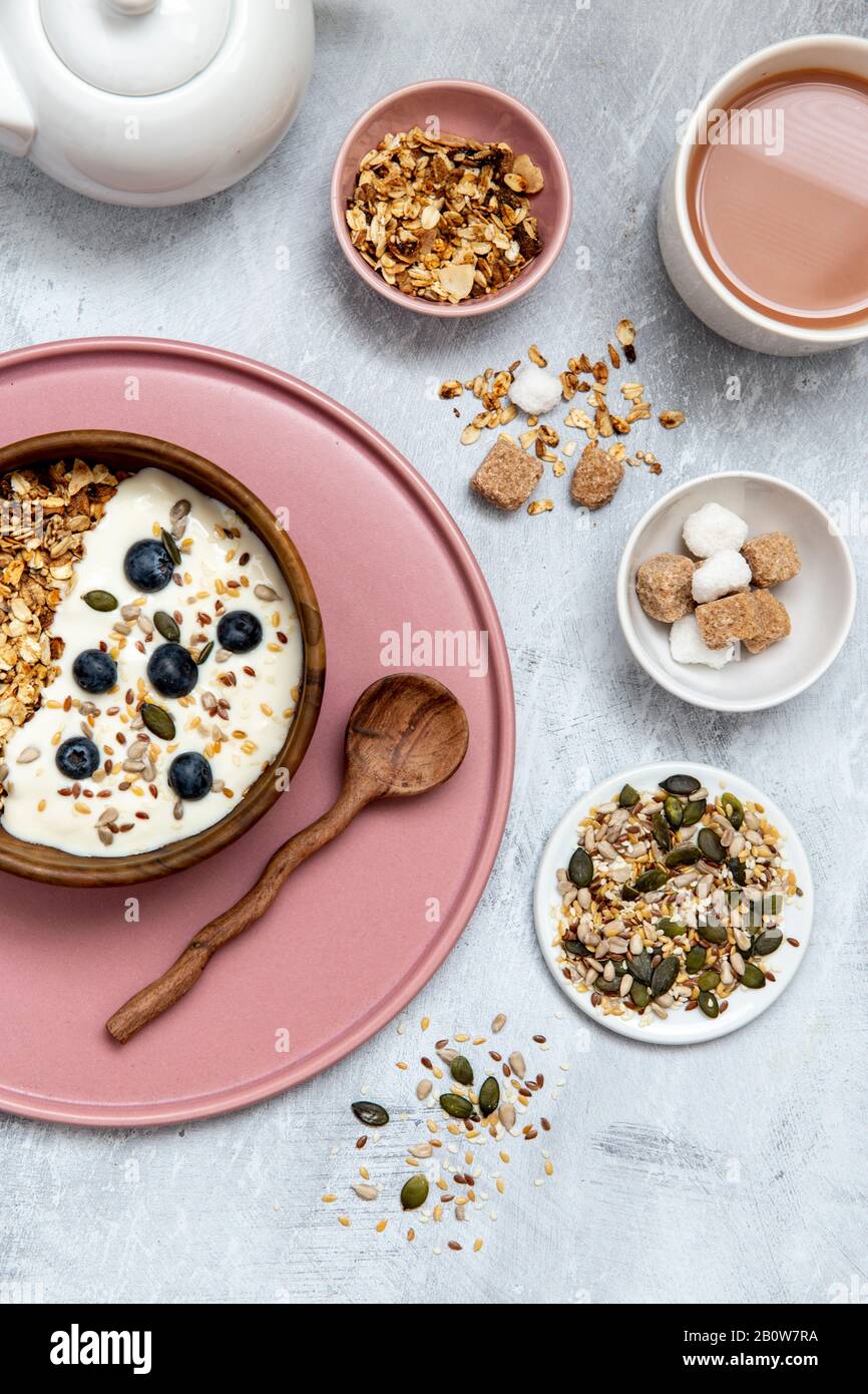 Bowl of muesli and blueberries on yogurt, assortment of seeds, brown and white sugar cubes Stock Photo