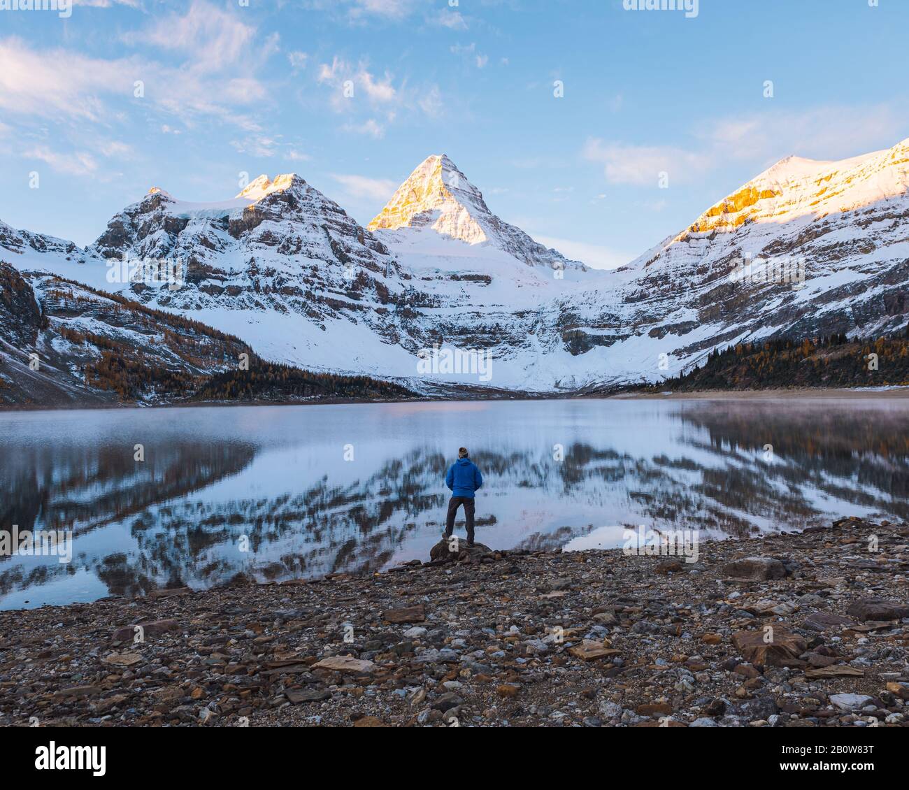 A man taking in the view across a lake to the panoramic view of Mount Assiniboine, Great Divide, Canadian Rockies, Alberta, Canada Stock Photo