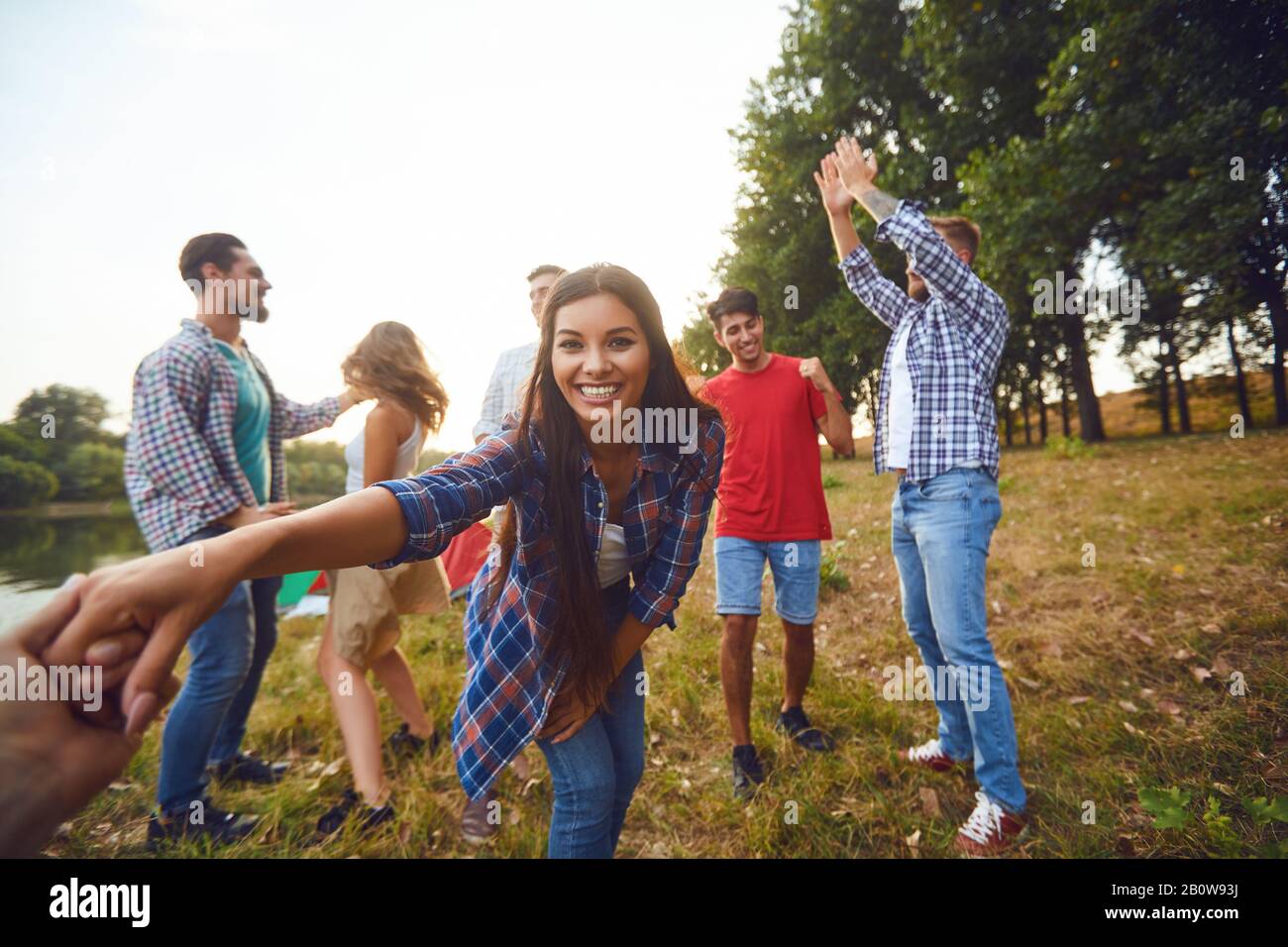 Friends have fun running along the lake on a picnic. Stock Photo
