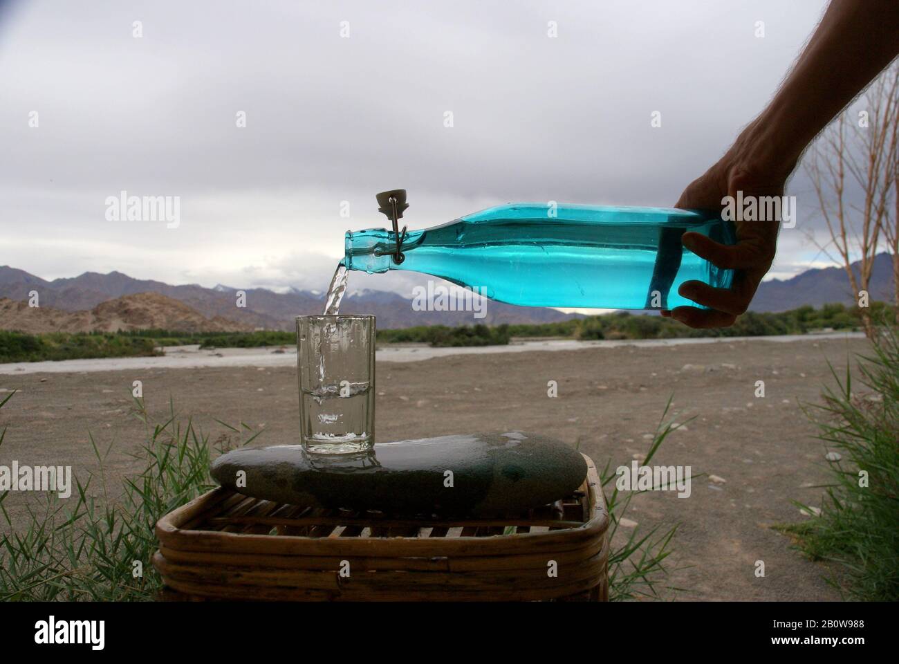 Serving fresh drinking water in a stylish turquoise glass bottle Stock
