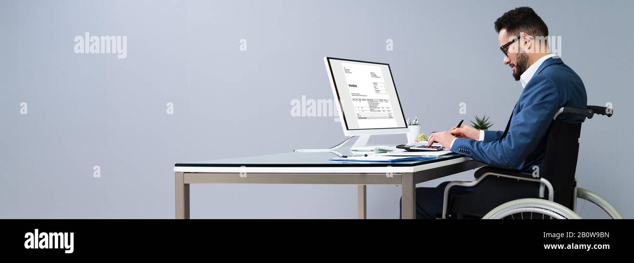 Businessman Sitting On Wheelchair And Using Computer Stock Photo