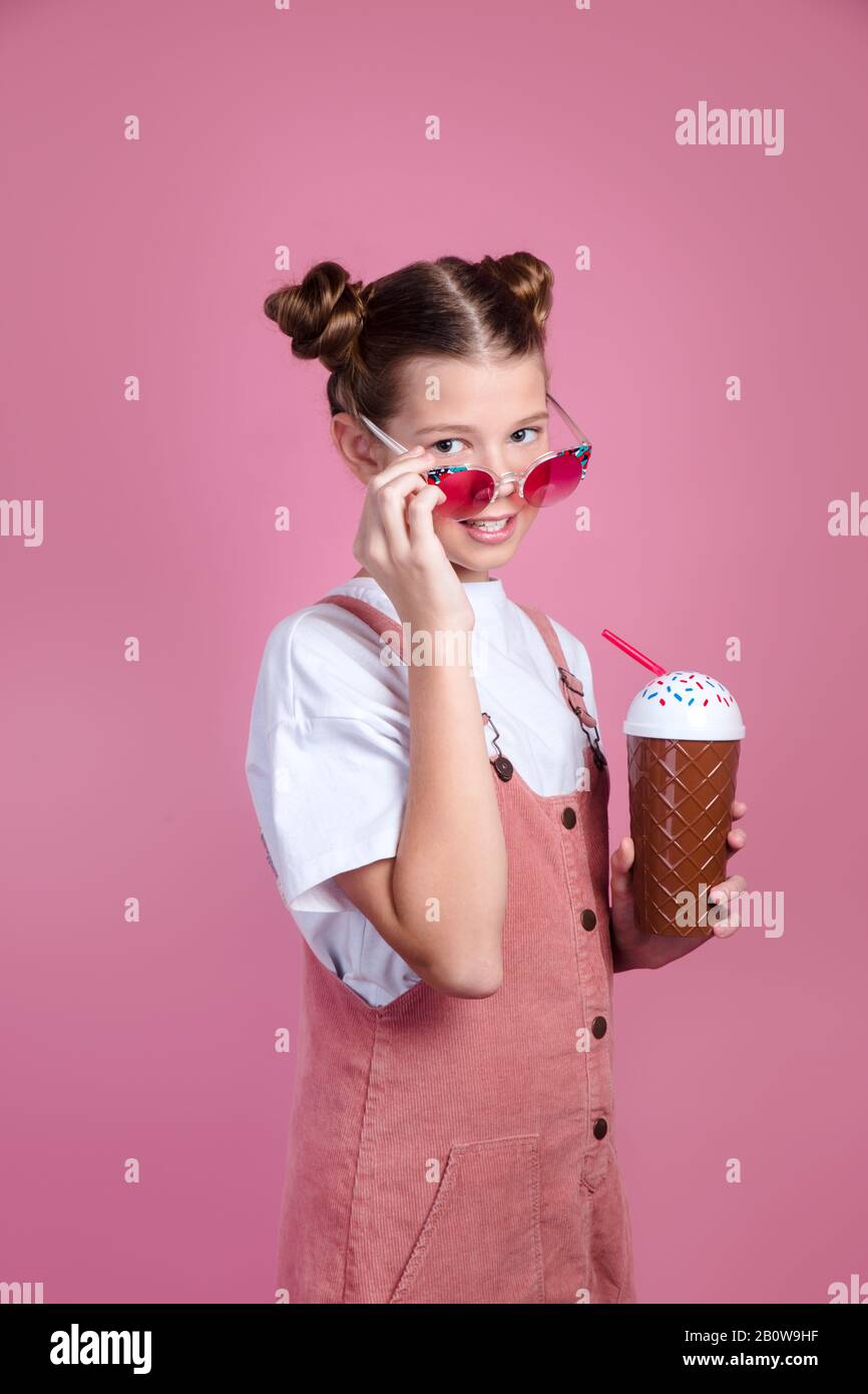 Young beautiful girl in sunglasses drinking a strawberry-flavored milkshake Stock Photo