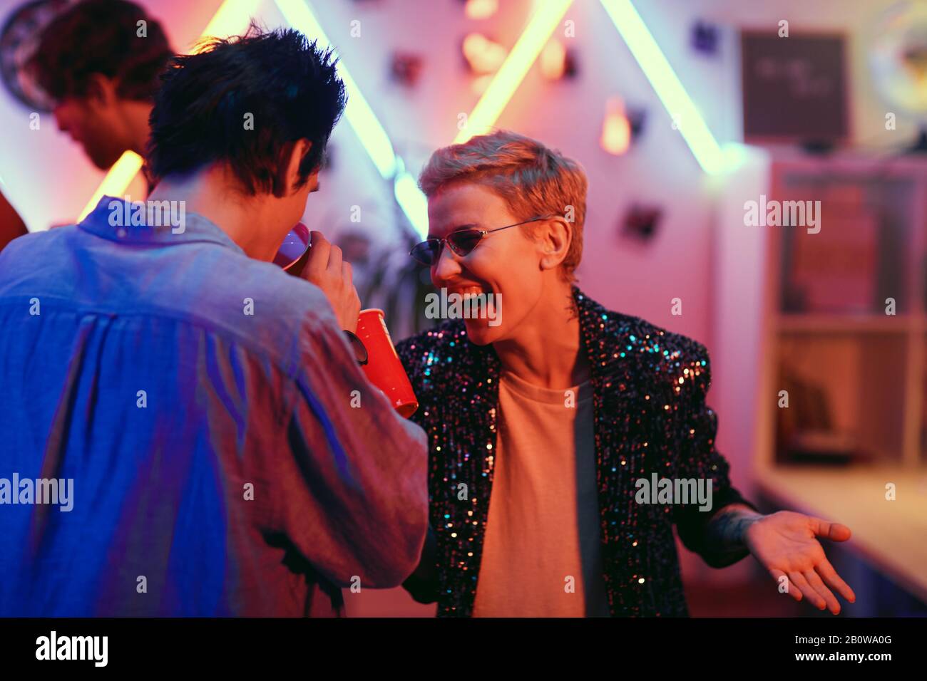 Young couple laughing and drinking beer from glasses while having fun