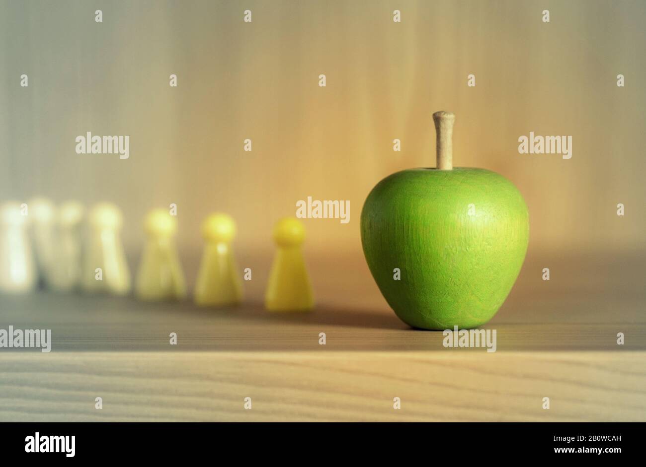 Playing pieces standing in line for an apple. Queue for food. Waiting line at a supermarket Stock Photo