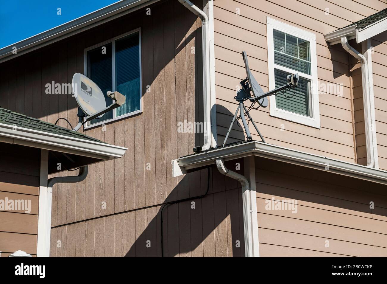 A pair of Direct TV Satellite dishes on neighboring houses. Stock Photo