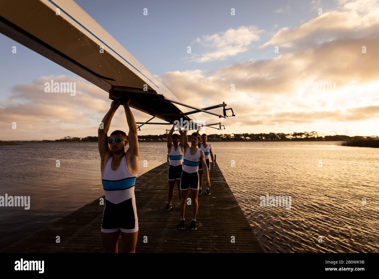 Teammates carrying the rowing boat together Stock Photo