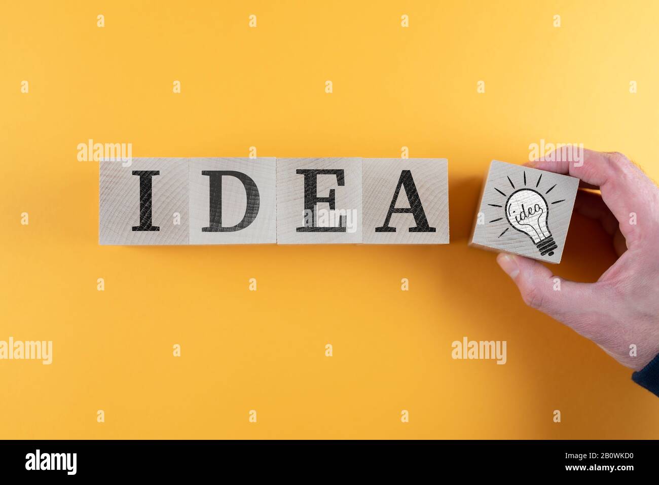 top view of wooden toy blocks with word IDEA and light bulb icon against orange background, innovation and creativity concept Stock Photo