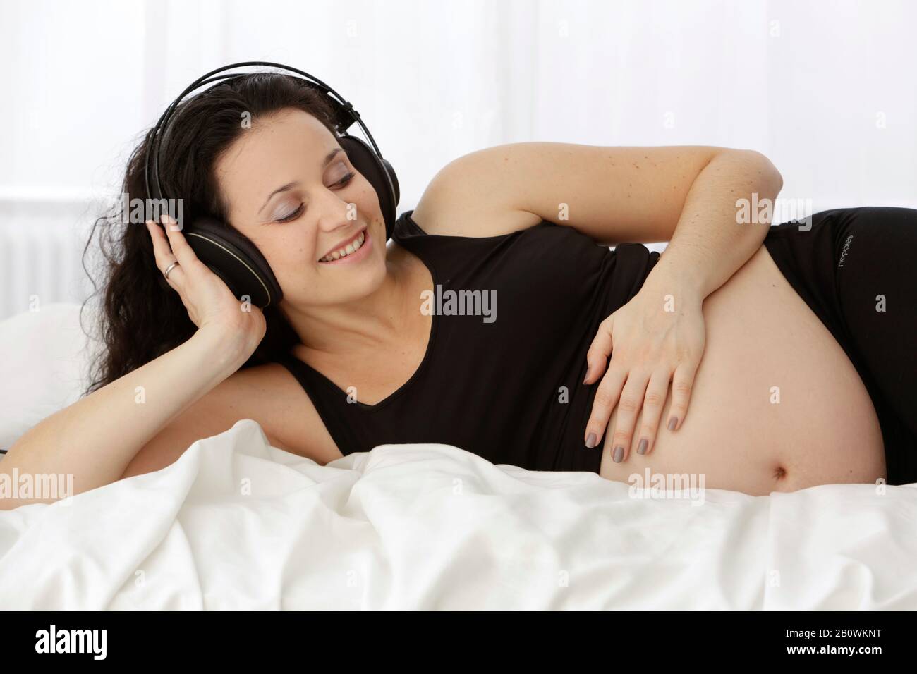 Pregnant woman listens to music with headphones Stock Photo Alamy