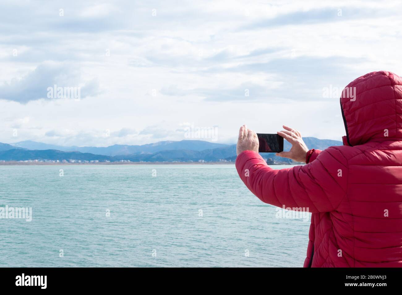 Unrecognisable man taking photos with smartphone. Admiring the nature, wanderlust Stock Photo
