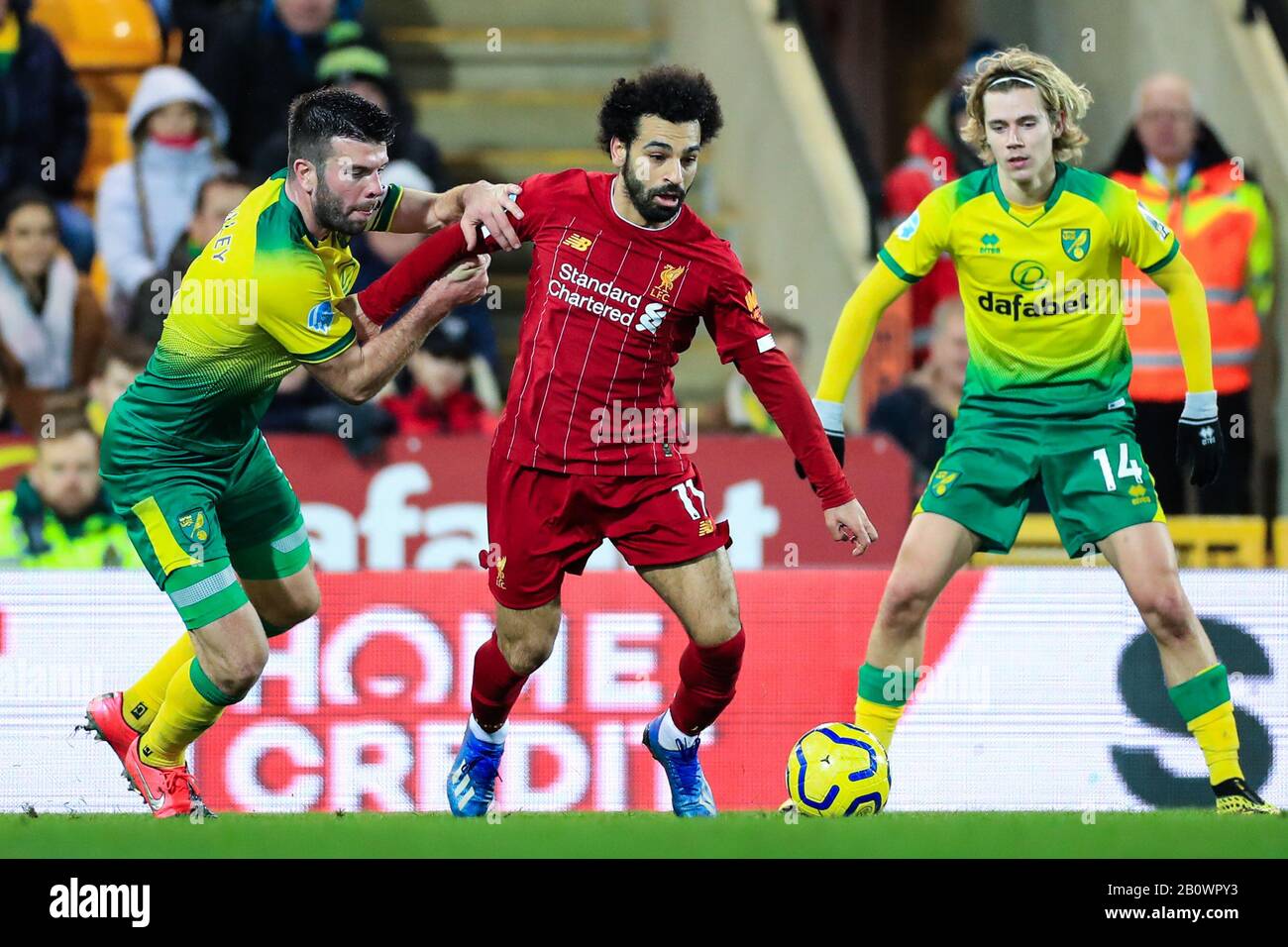 15th February 2020, Carrow Road, Norwich, England; Premier League, Norwich City v Liverpool : Mohamed Salah (11) of Liverpool is flanked by Grant Hanley (05) of Norwich City and Todd Cantwell (14) of Norwich City Stock Photo