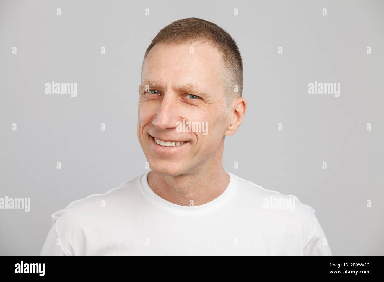 Middle-aged smiling man headshot in a white t-shirt. Stock Photo