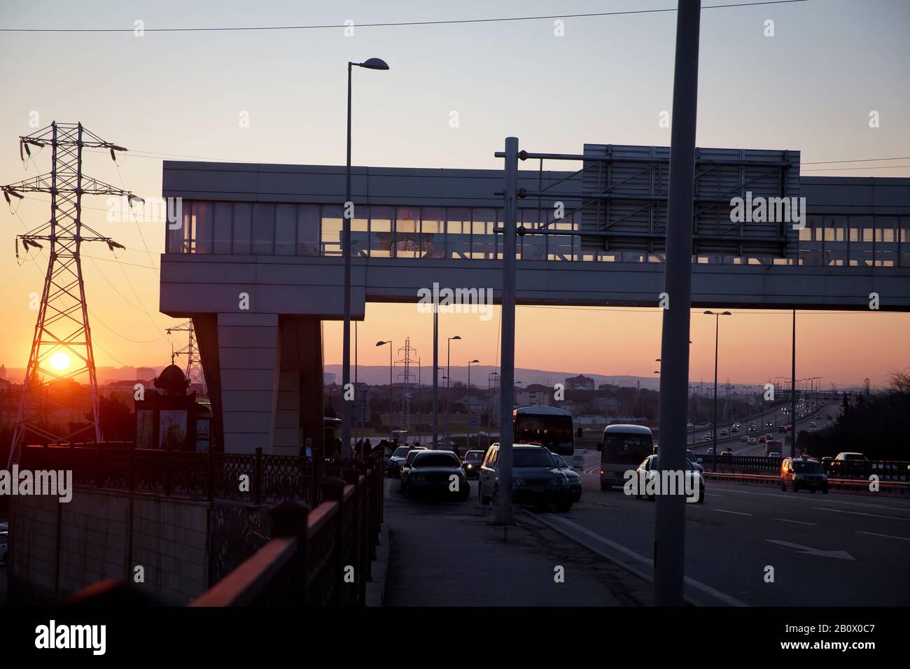 Bridges crossing people without a roof. Sunset . Road .Electricity transmission power lines High voltage tower . The pedestrian crossing bridge . Stock Photo