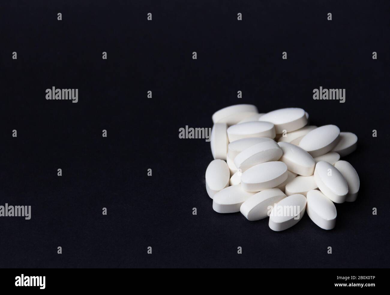 White pills on black background. Free copy space. Medical concept. Stock Photo