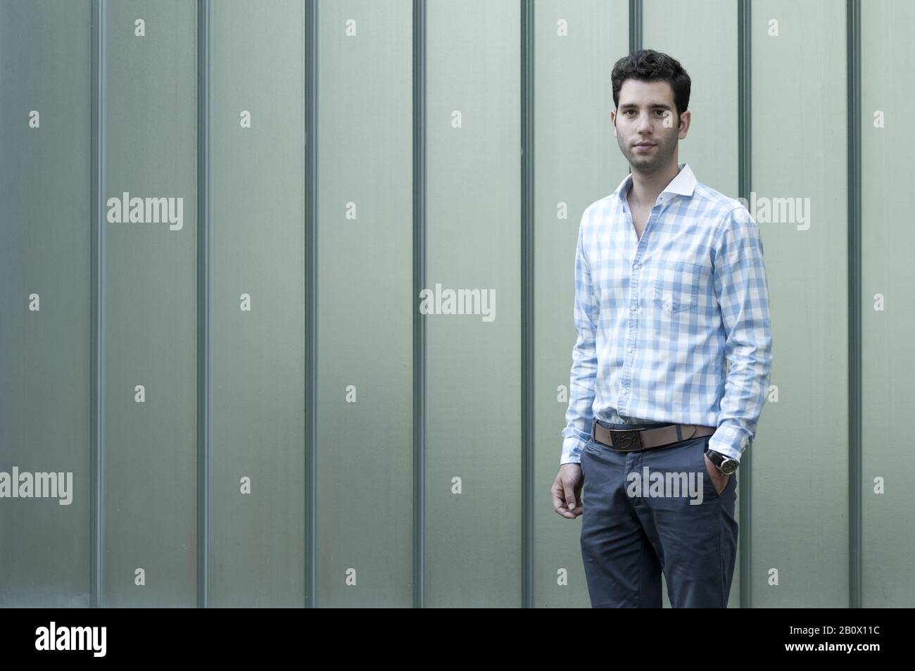 Young man in shirt stands in front of house wall, Stock Photo