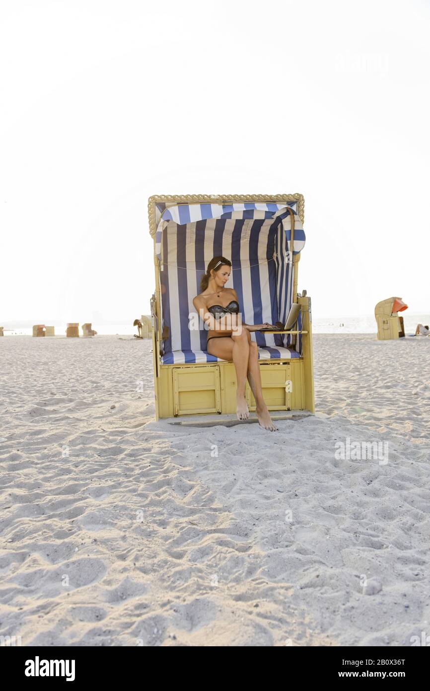 Young woman with laptop on the beach, Niendorf on the Baltic Sea, Schleswig-Holstein, Germany, Stock Photo