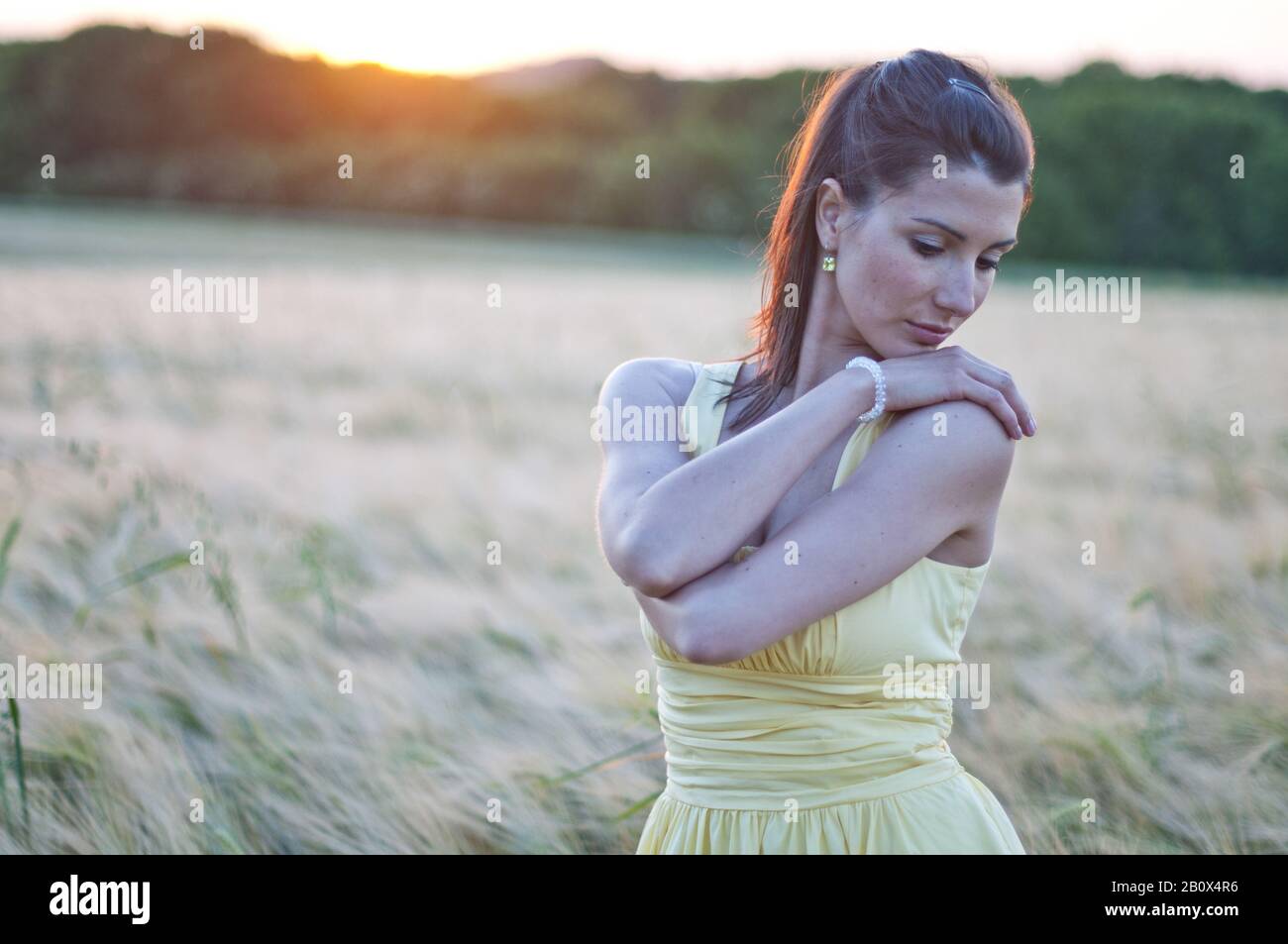 Young woman in a grain field at sunset Stock Photo - Alamy
