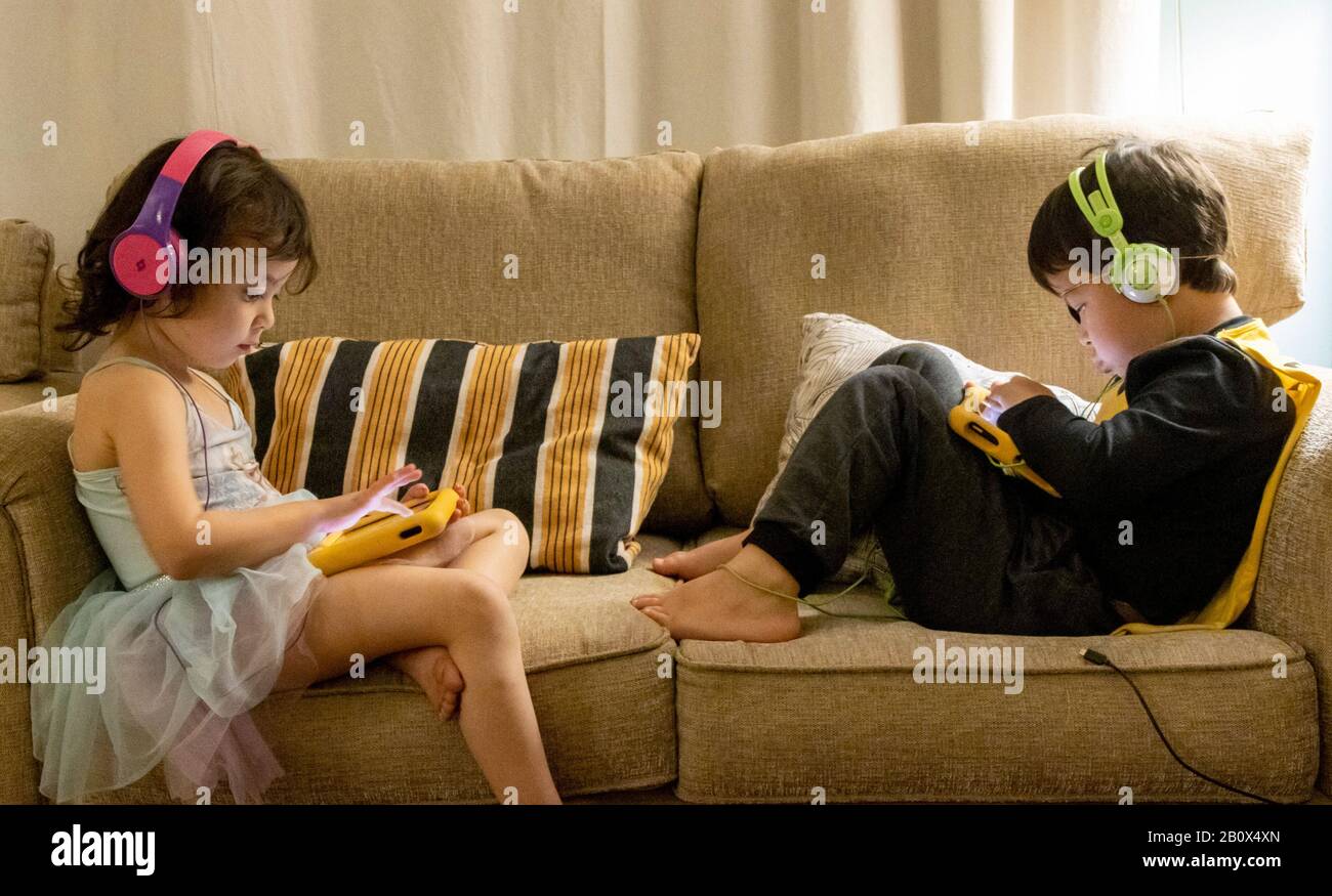 children playing on Amazon Fire tablet listening to headphones Stock Photo