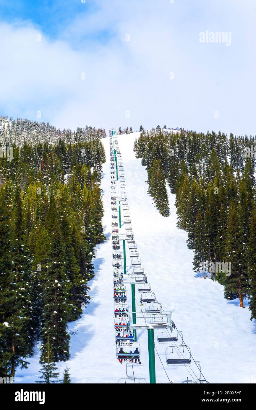 Long chair lift ride carrying skiers up the ski slope in the Canadian