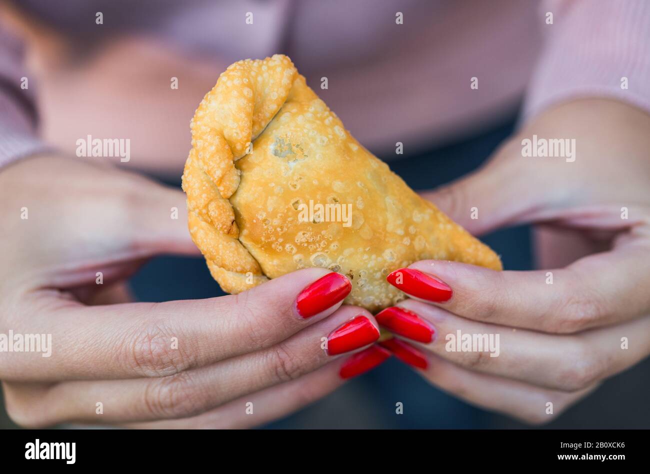 Eating traditional fried Spanish and Argentine empanadas at street food market. Stock Photo