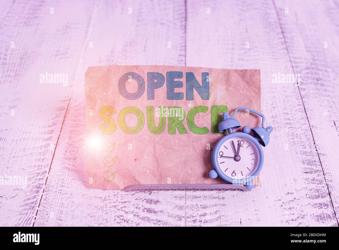 Handwriting text writing Open Source. Conceptual photo denoting software which original source code is made free Mini blue alarm clock stand tilted ab Stock Photo
