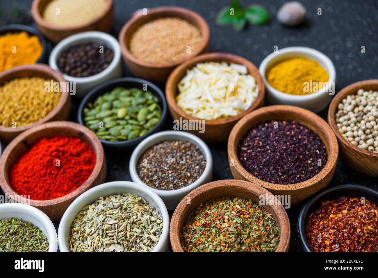 Variety of colorful spices, herbs, and seeds on black stone background ...
