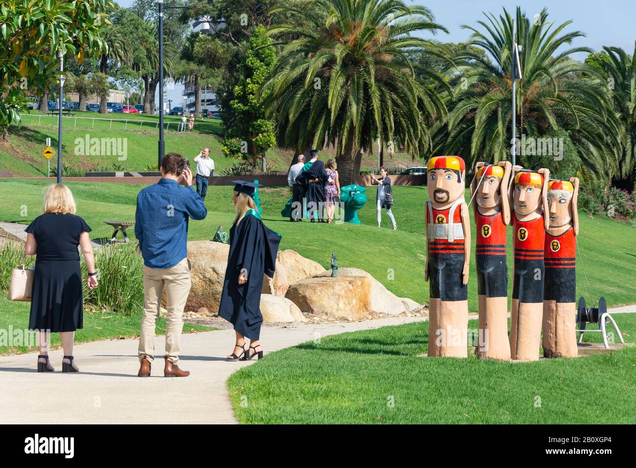 Graduation students and lifesaver character bollards on harbour foreshore, Geelong, Grant County, Victoria, Australia Stock Photo