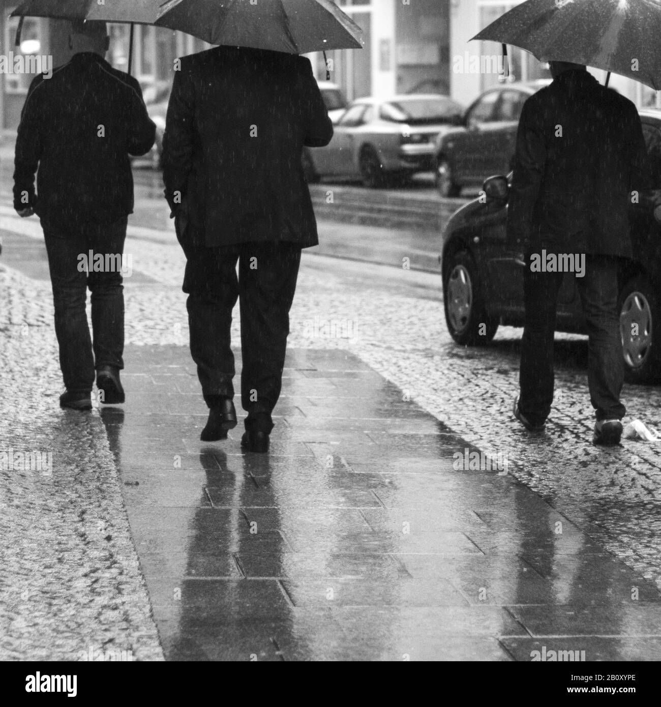 Three men run in the rain Stock Photo