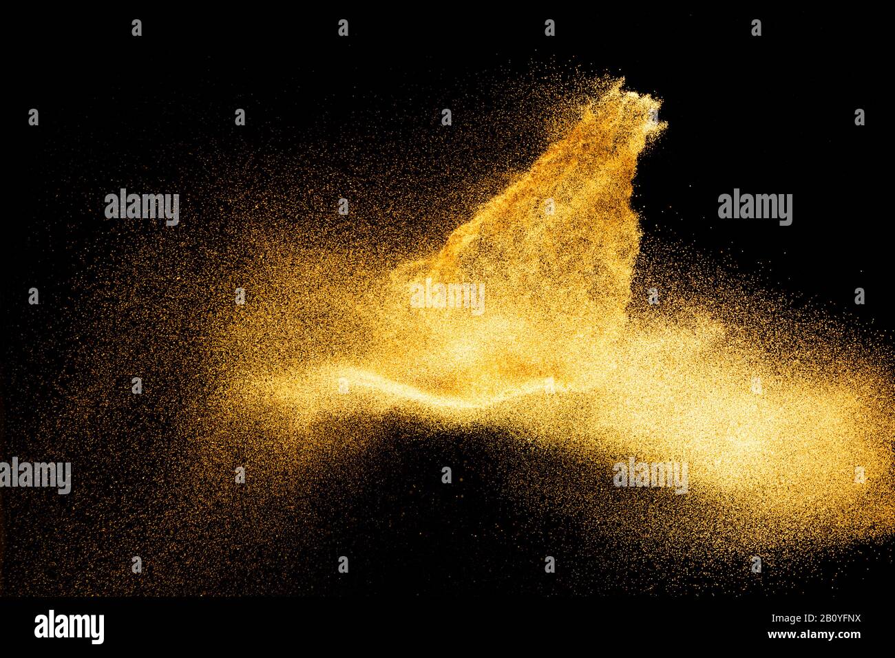 Golden sand explosion isolated on black background. Abstract sand cloud