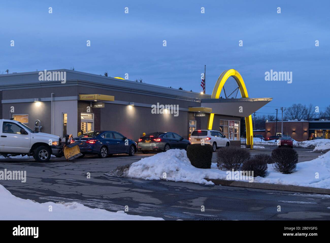 Utica, NY - Feb 12, 2020: Evening View of McDonald's Pickup Window with Cars Line Waiting for Orders. Stock Photo