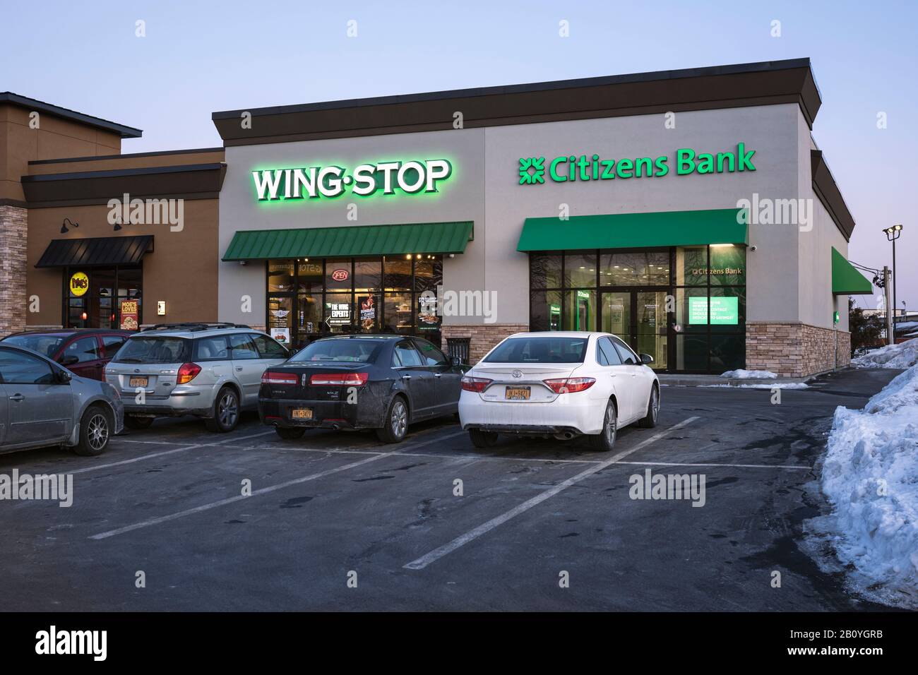 Utica, New York - Feb 21, 2020: Evening view of Citizens Bank and Wing Stop Restaurant, Casual counter-serve chain serving a variety of chicken wings Stock Photo