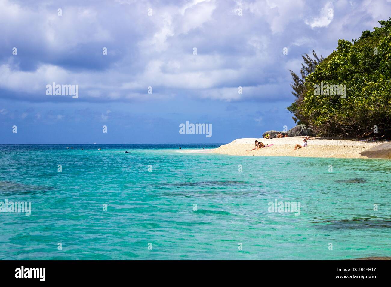 Bathers relax on the sands of Nudey Beach, Fitzroy Island, in the crystal clear waters of the Coral Sea near the coast of Queensland Australia. Stock Photo
