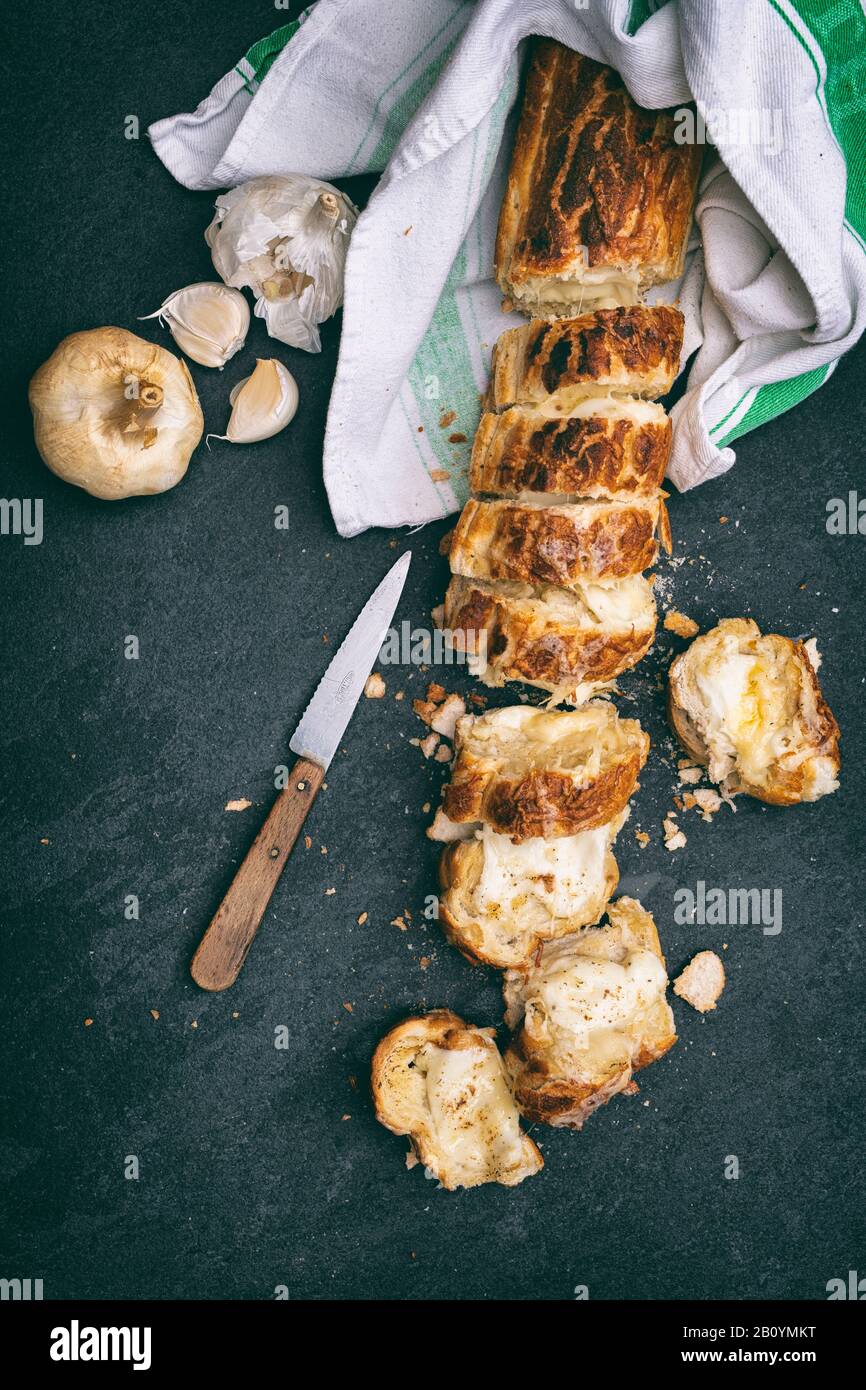Homemade garlic french bread and melted cheese on a slate background Stock Photo