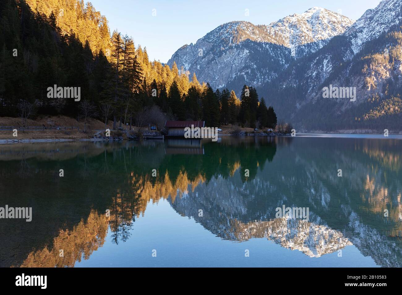 Reflection of mountain peaks and trees at Plansee (Plan Lake) on a winter morning, Alps, Austria. Morning tranquility. Warm winter 2020 in Europe. Stock Photo