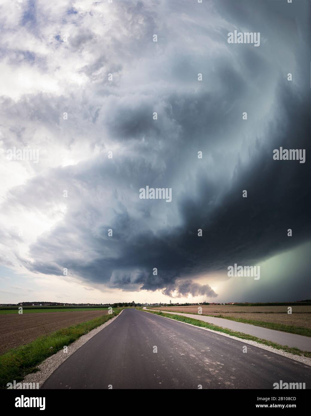 Panorama of a super cell with a low-lying wall cloud, a healthy upwind base and a glowing green precipitation core over a country road near Heilsbronn, Bavaria, Germany Stock Photo