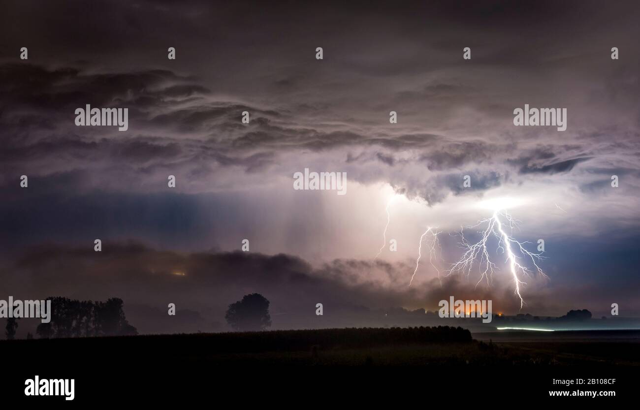 Strong, branched lightning bolts behind the fog-swallowed mountain of Amöneburg, Hessen, Germany Stock Photo