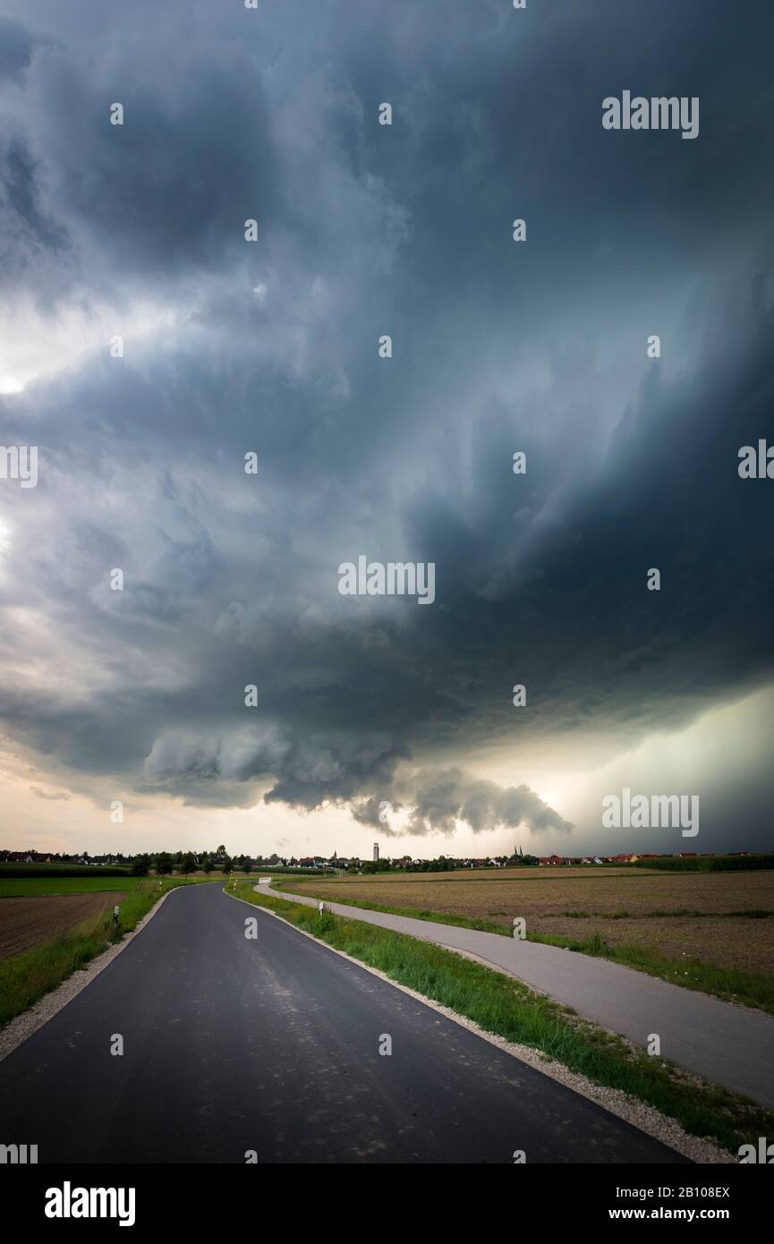 Low-hanging wall cloud, healthy updraft base and heavy precipitation core of a classic supercell over a country road near Heilsbronn, Bavaria, Germany Stock Photo