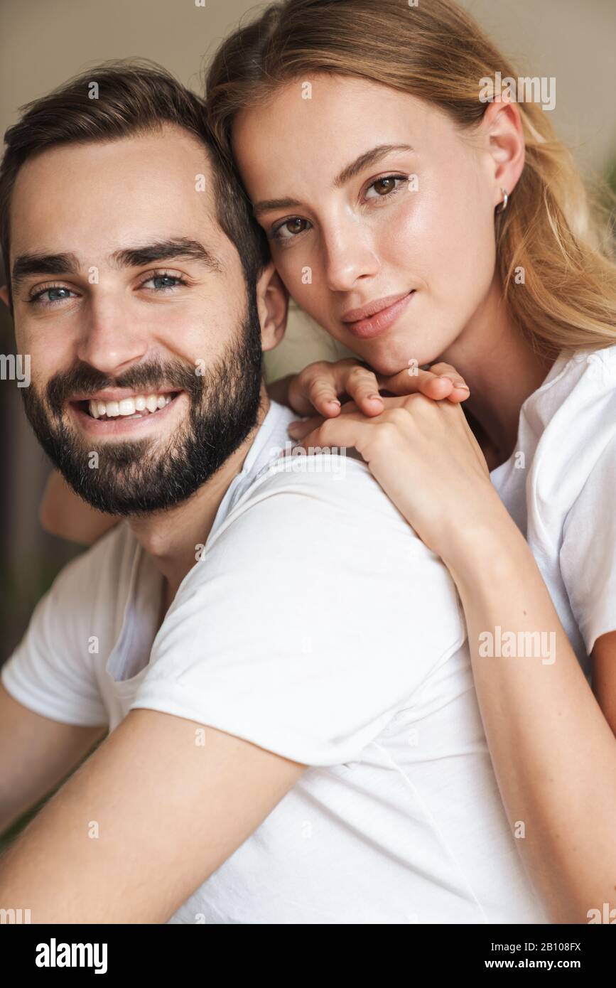 Beautiful happy young couple in love embracing at home, looking at ...