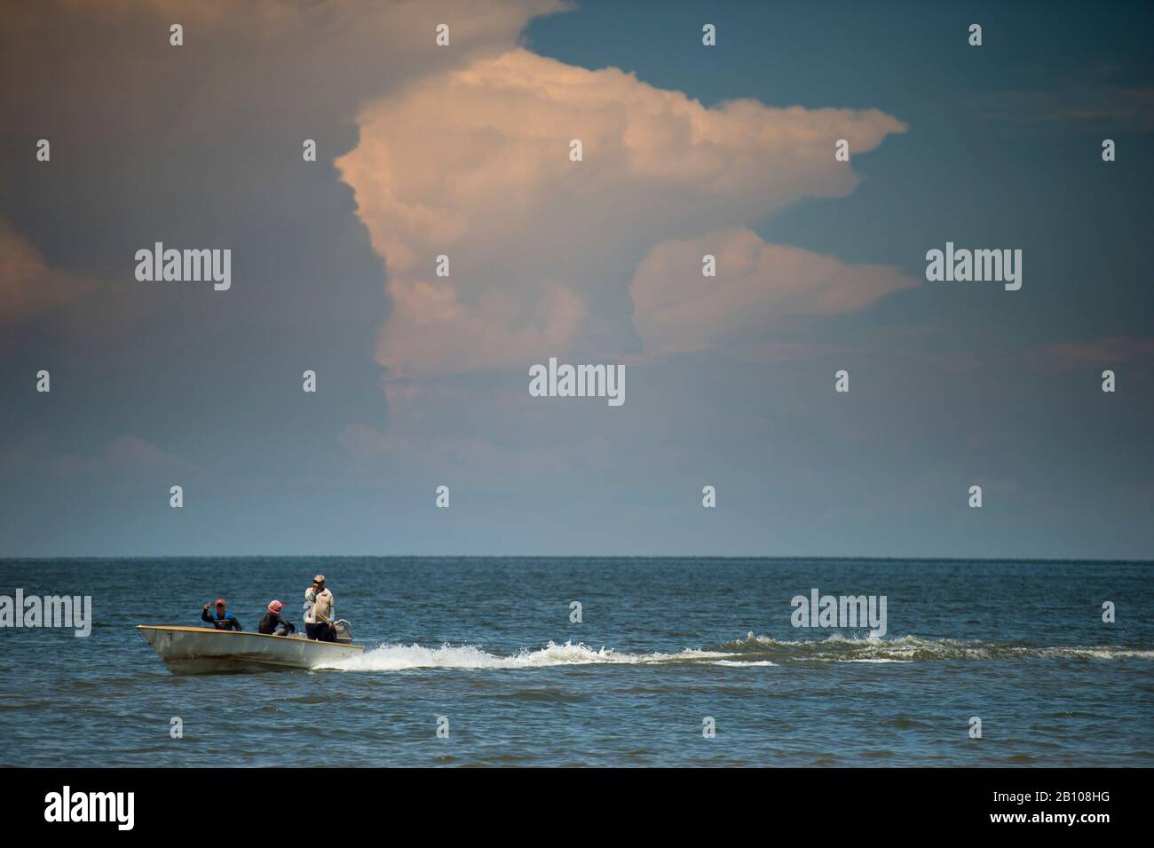 Hooded fishermen sail along Lake Maracaibo in front of newly formed storm clouds (Catatumbo thunderstorm, the place with the highest lightning density on earth) Ologa, Zulia, Venezuela, South America Stock Photo