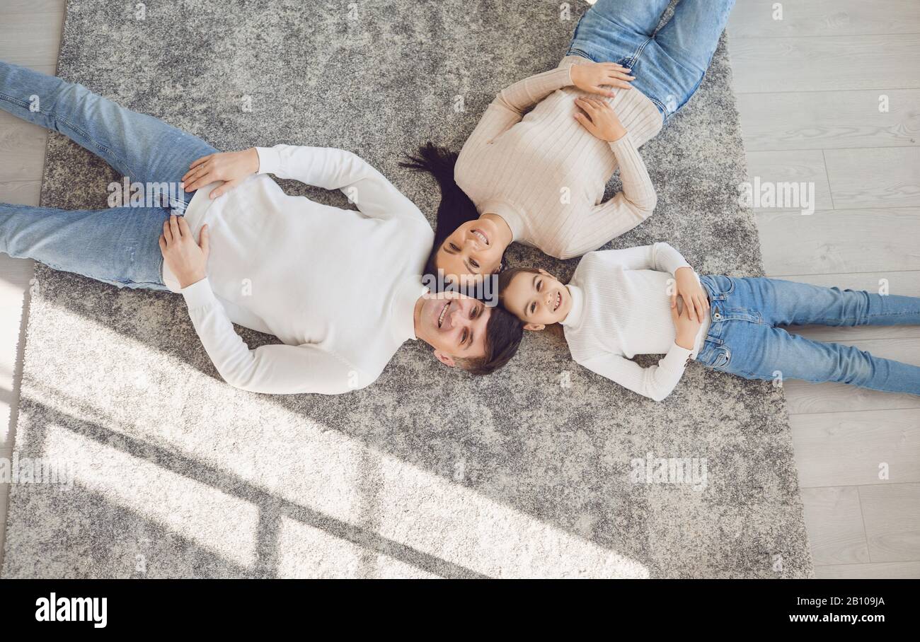 Top view.Happy smiling family hugging while lying on the floor in the room at home. C Stock Photo