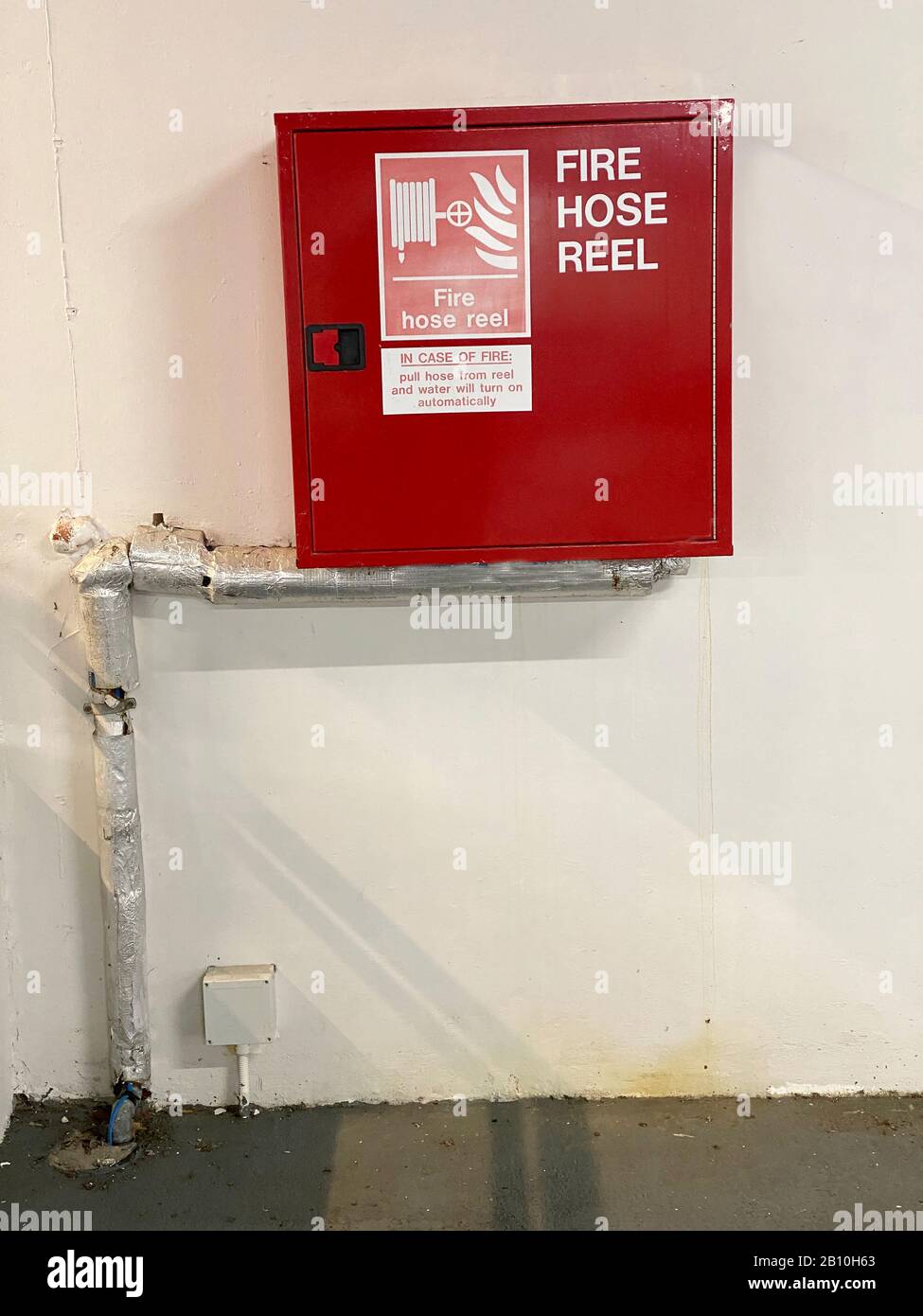 Fire hose reel red and insulated pipe outdoors in public work place Stock Photo