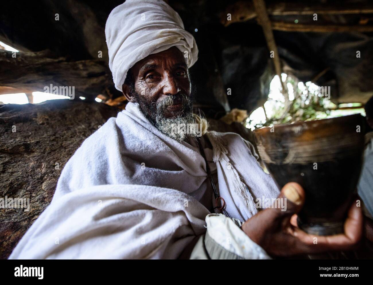 Ethiopian Orthodox Church priest near the Abba Yohanni Church drinks Tej, the local alcoholic beverage, Tigray, Ethiopia Stock Photo