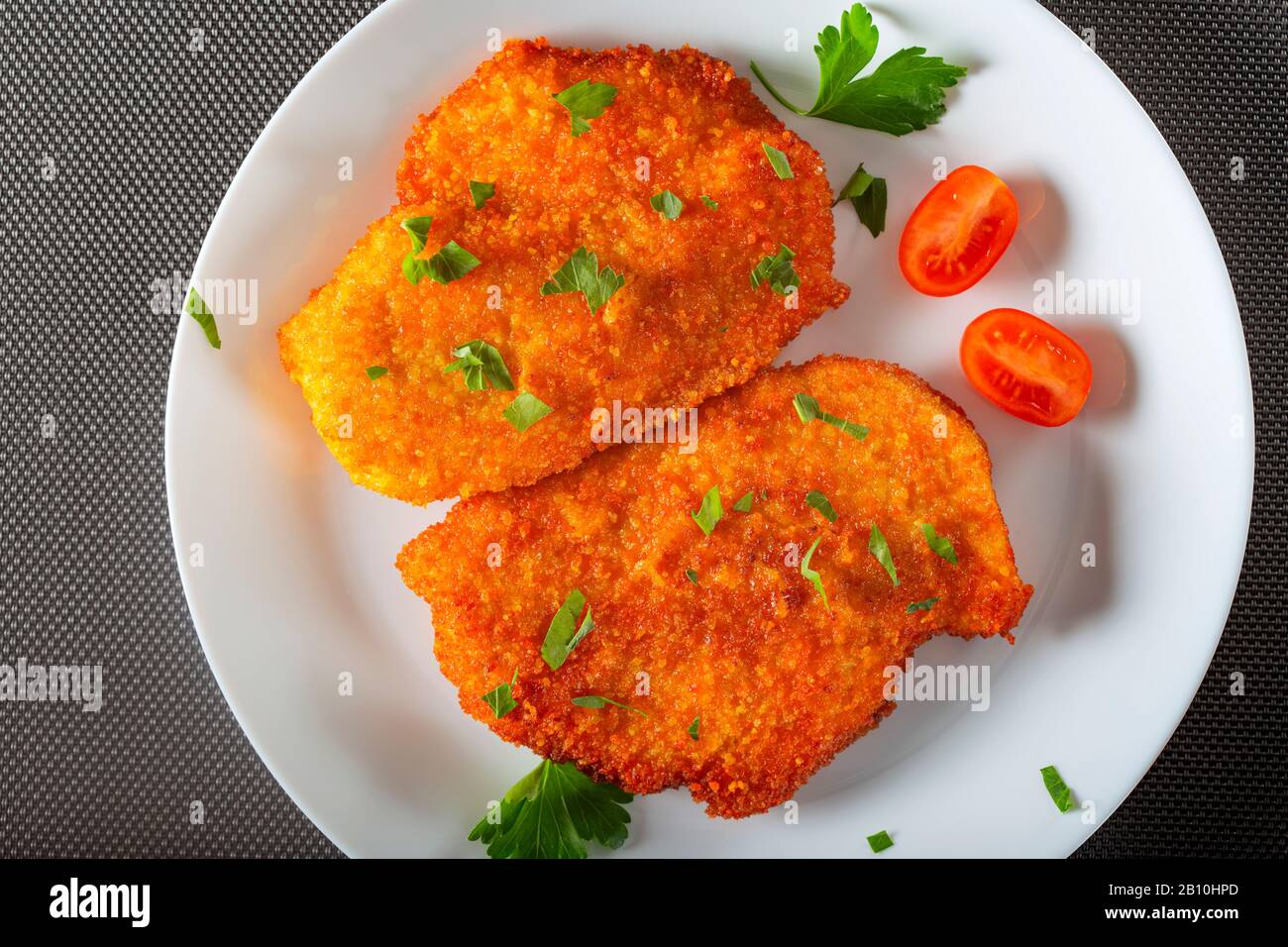 Chicken schnitzel on plate with herbs - top view Stock Photo